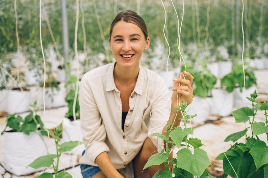 Smiling woman in a greenhouse showcasing modern indoor farming techniques.